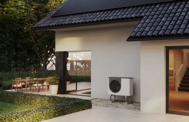 Outdoor unit of a WATERKOTTE air source heat pump in front of the façade of a new building.