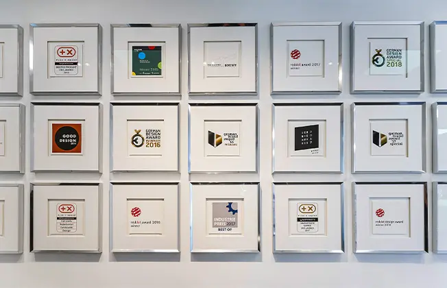 Wall displaying numerous framed awards for design quality and user-friendliness.