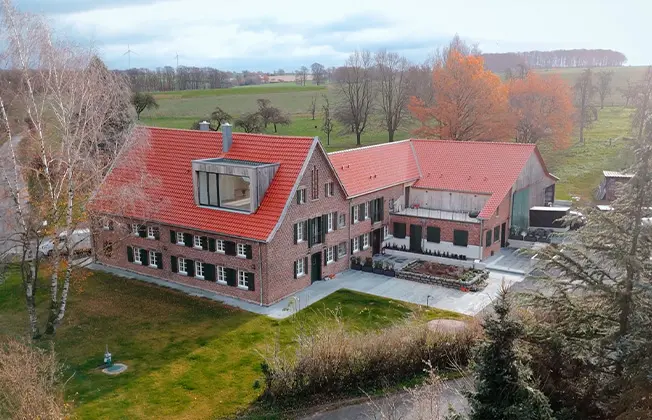 Reference: Drone shot of renovated farmhouse with brick and oak façade.