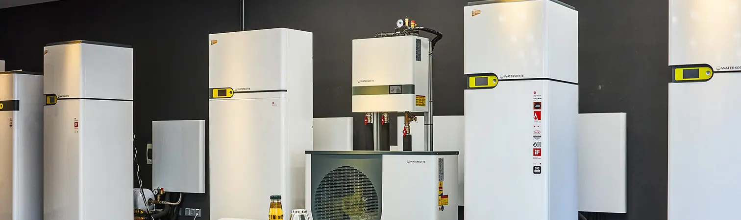 Waterkotte heat pumps on display in the showroom stand in front of an anthracite-colored wall.