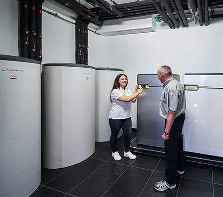 A Waterkotte employee advises a customer in the boiler room on sustainable heat pump systems from Waterkotte.