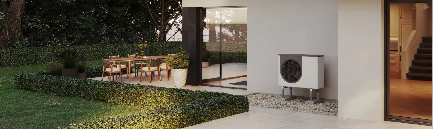 Outdoor unit of an air source heat pump in front of a new building.