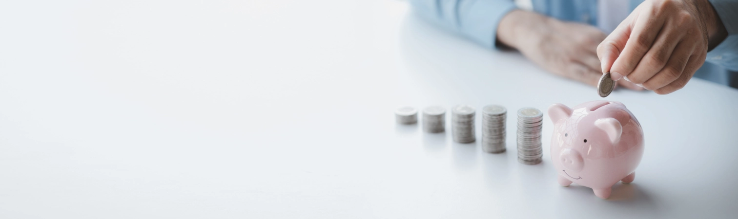 Person wirft Münze in Sparschwein.