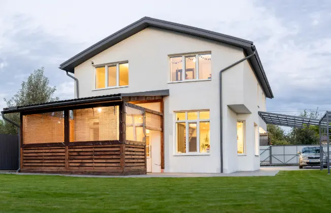 Single-family home at dusk with lights on inside.