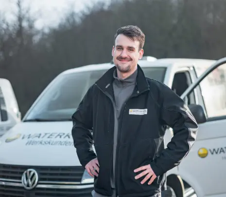 A WATERKOTTE technician stands in front of a service vehicle with the words “Factory Customer Service” written on it and smiles.