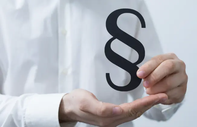 Person in a white shirt holding a paragraph sign in their hand.