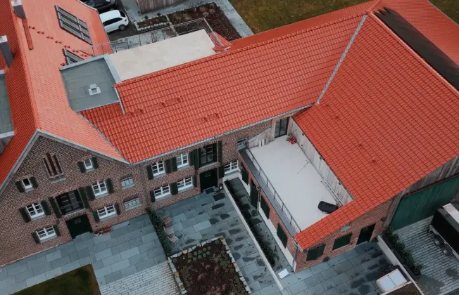 Drone view of the farmhouse with a view of the roof and rooftop terrace.
