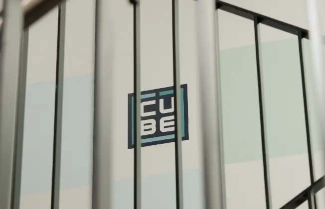 View of the CUBE administrative building logo seen through a staircase railing.