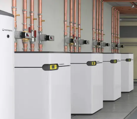 Buffer storage tank and several heat pumps in cascade in the basement of an apartment building.
